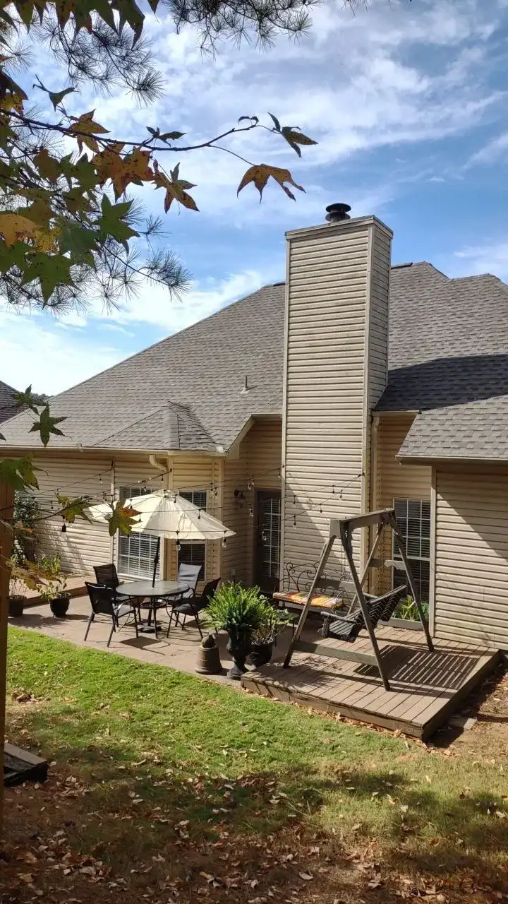 A backyard patio with a swing set, table, chairs, and a fireplace.